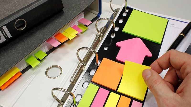 A close-up of a binder with many sticky notesDescription automatically generated